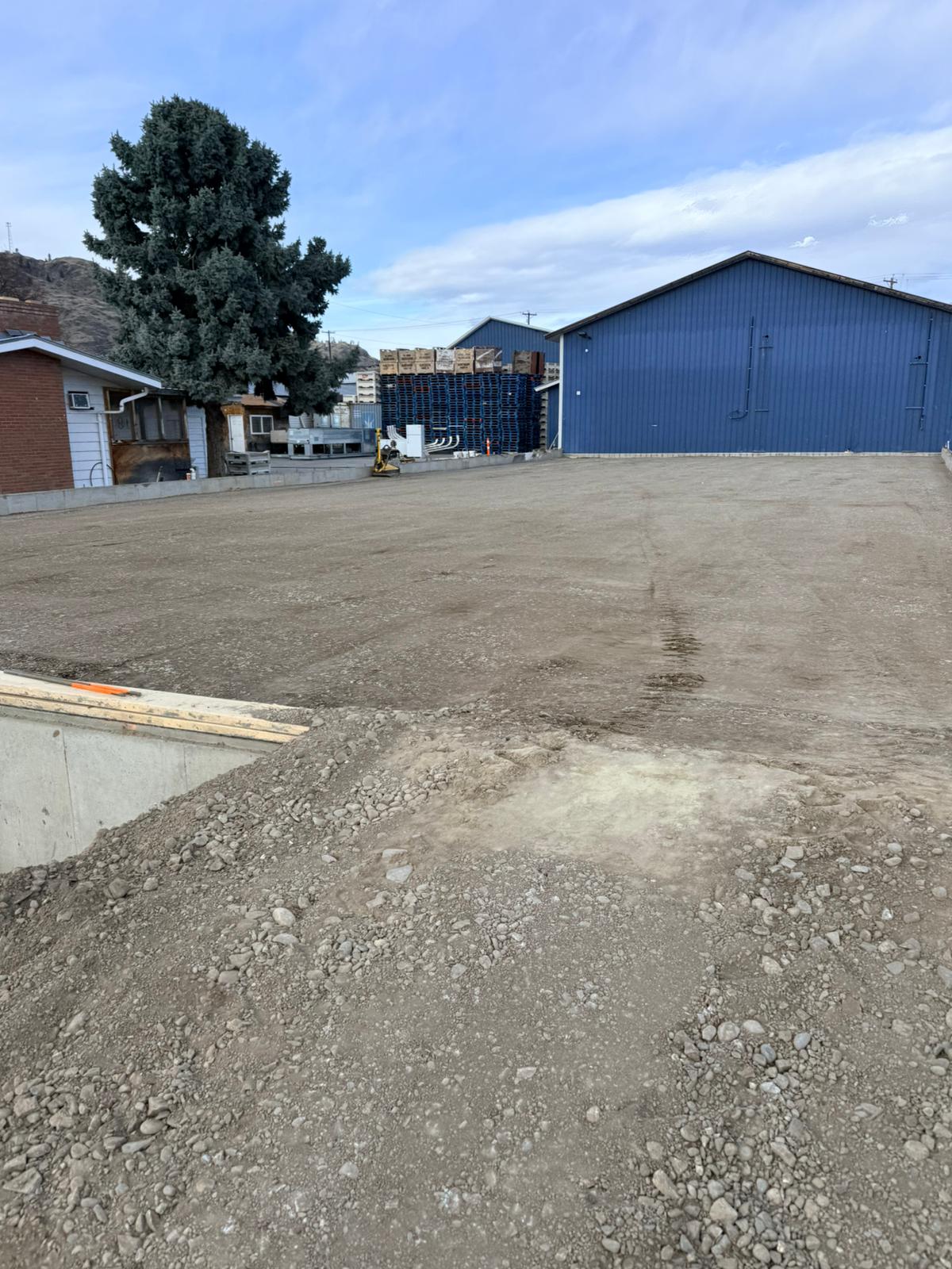 Finished graded commercial site with blue warehouse building in South Okanagan