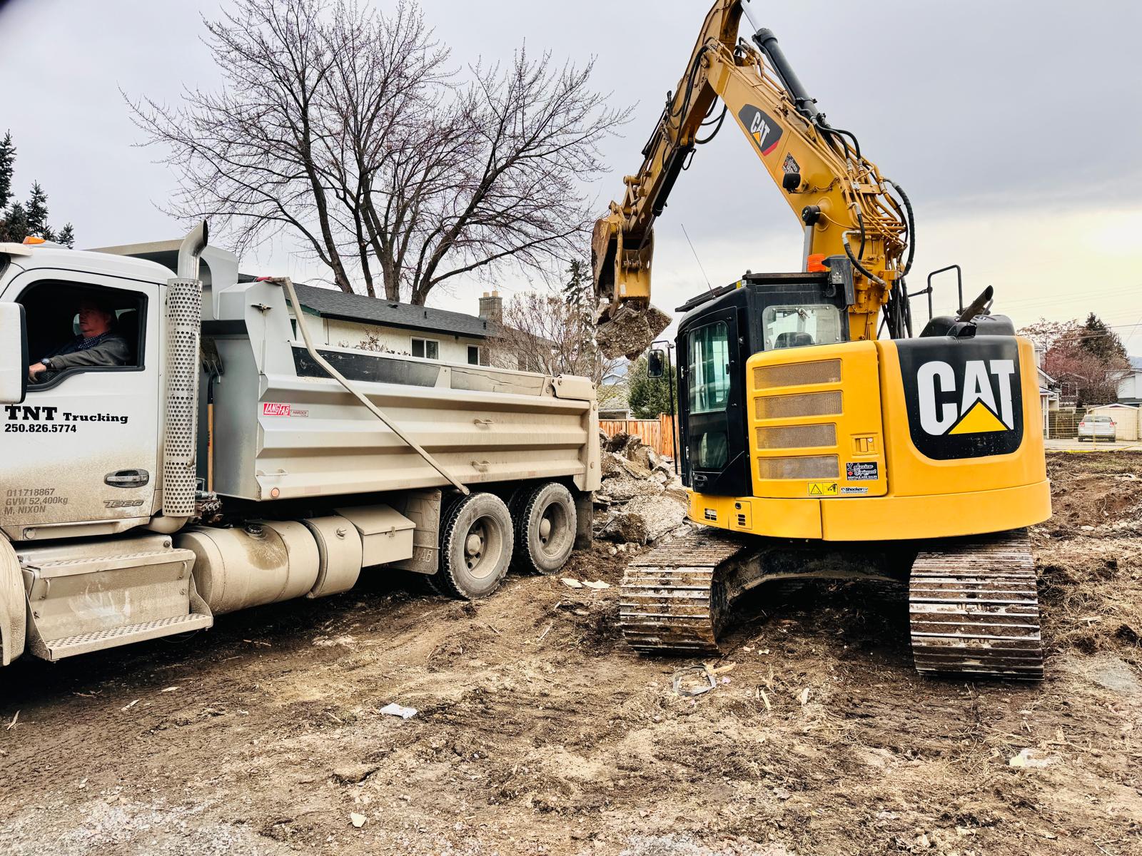 CAT excavator loading concrete demolition debris into dump truck