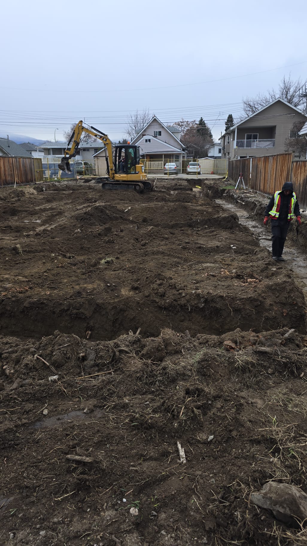 Excavation crew and CAT excavator working residential site in Okanagan